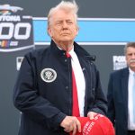 Donald Trump holding MAGA cap Daytona 500