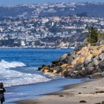 A woman walks on the beach in San Clemente